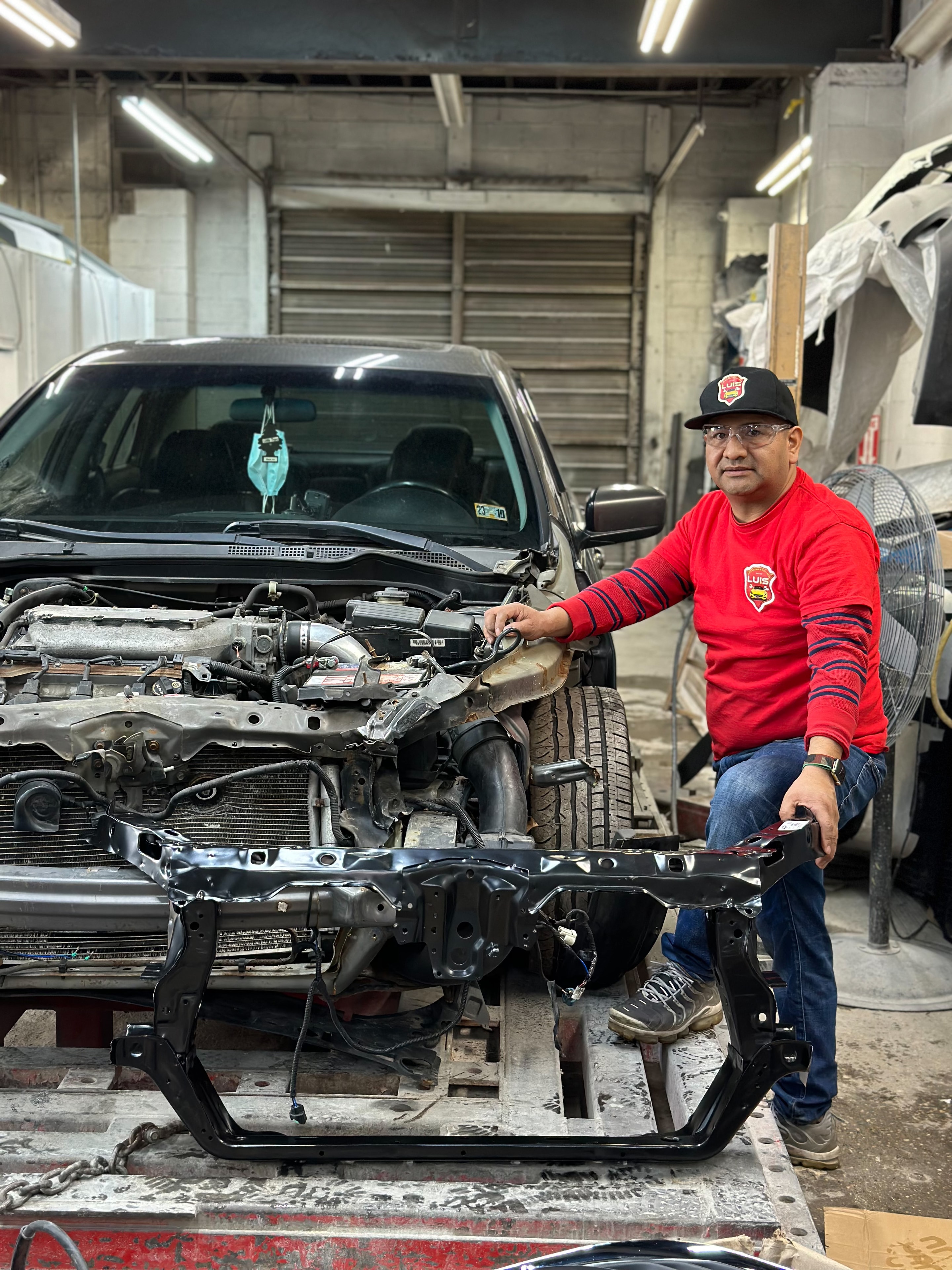 Painter crouching beside a masked car in the spray booth
