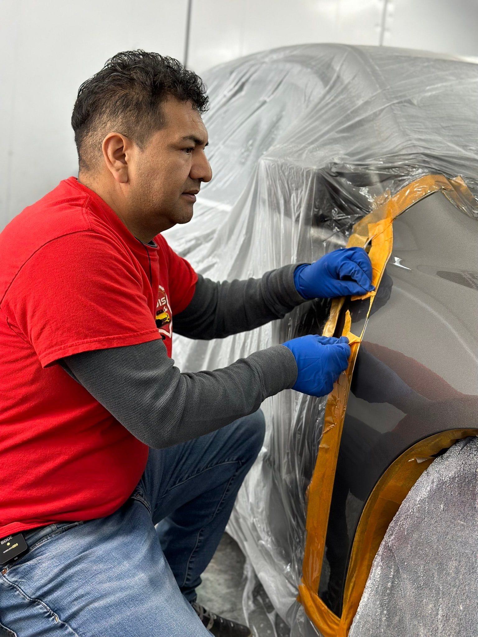 Painter applying fresh metallic paint in a spray booth