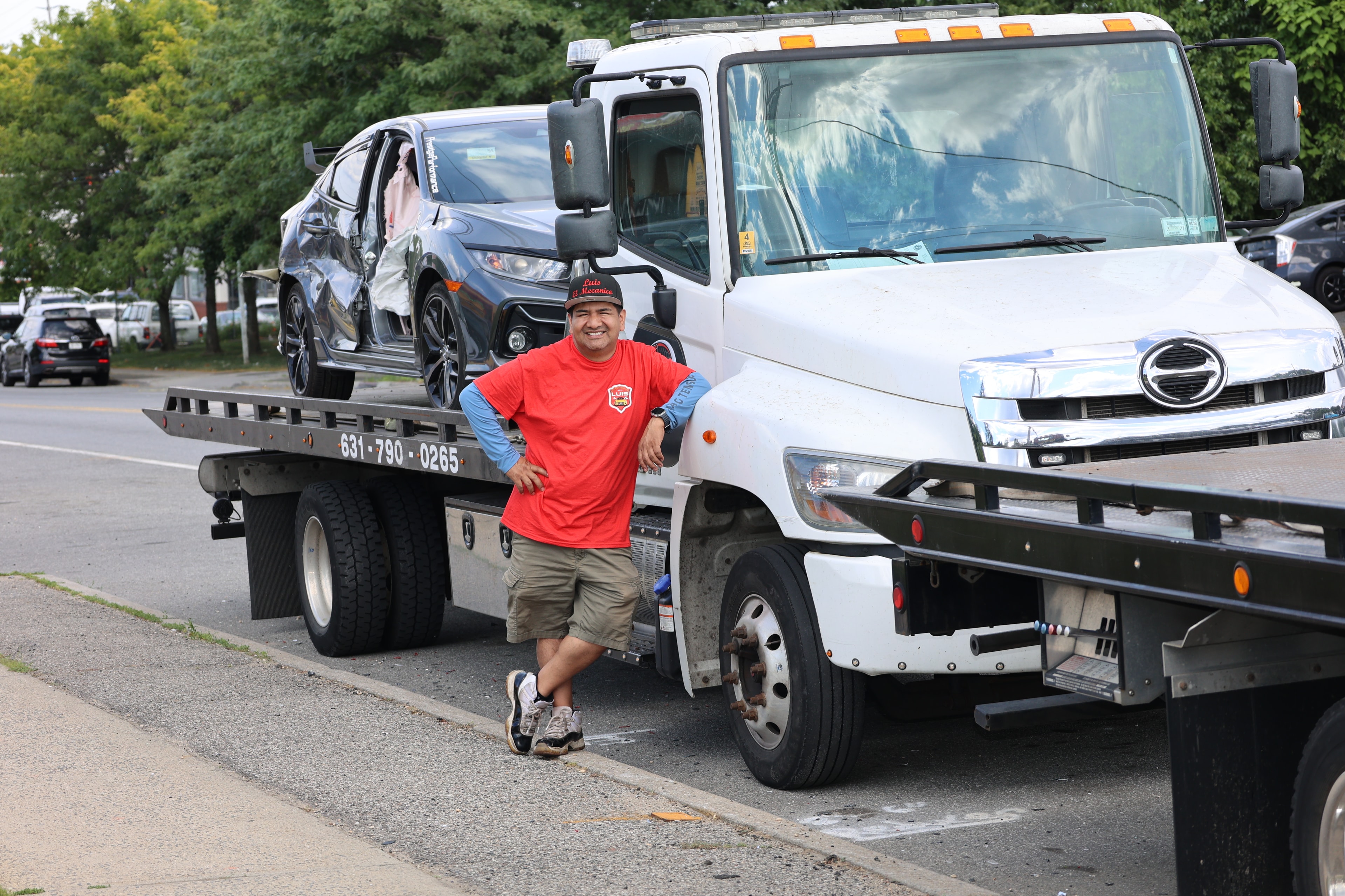 Tow truck loading a car on a flatbed on a city street